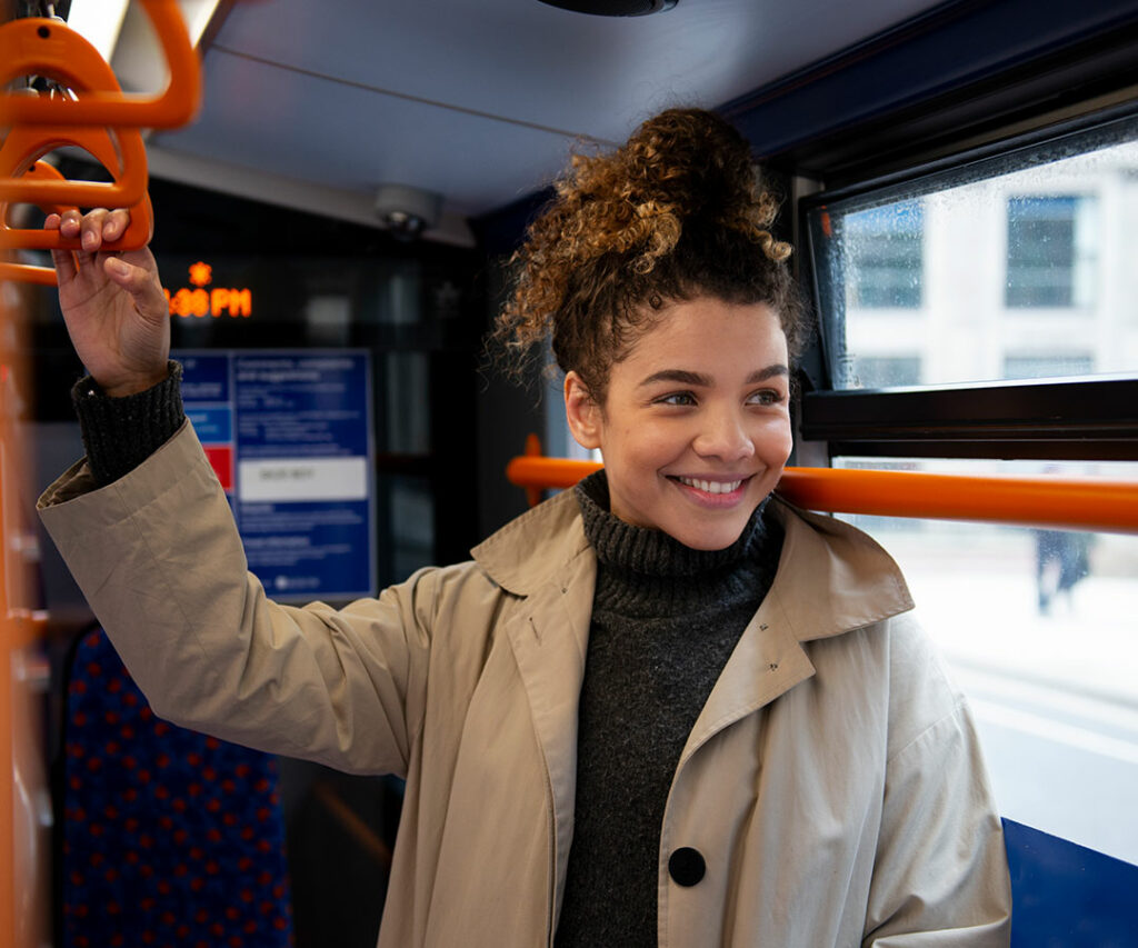 Estudia y trabaja en Gozo Malta. Chica joven feliz en transporte público sosteniendose de los pasamanos